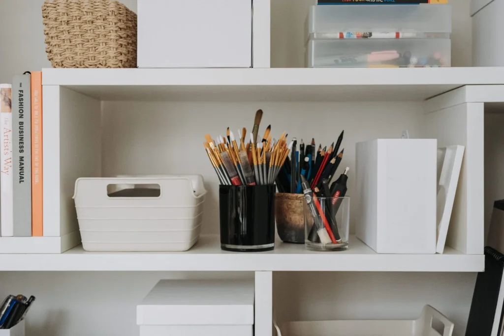 Renter-friendly storage ideas for a small apartment: a white shelving unit with a woven basket, fabric bin, and various containers keeping everyday supplies organized.